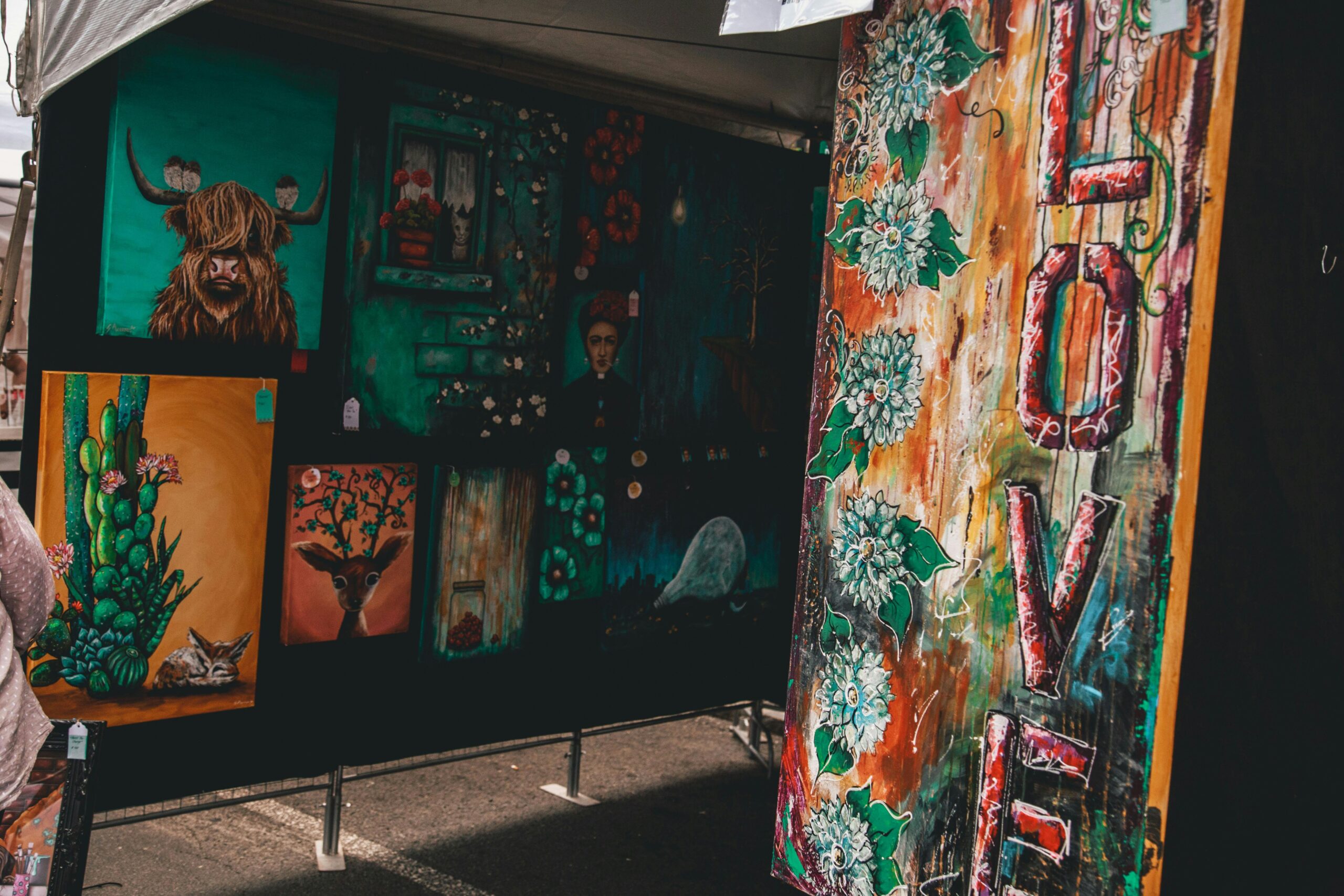 Colorful display of diverse artworks at an outdoor art fair highlighting contemporary styles.