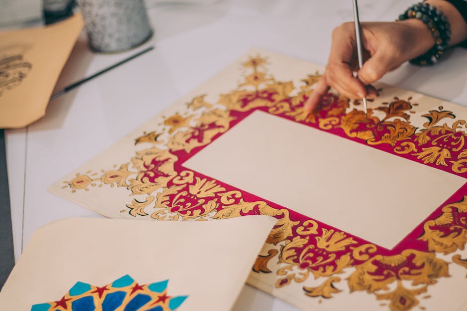 Artist hand painting intricate floral design on paper in a studio setting.